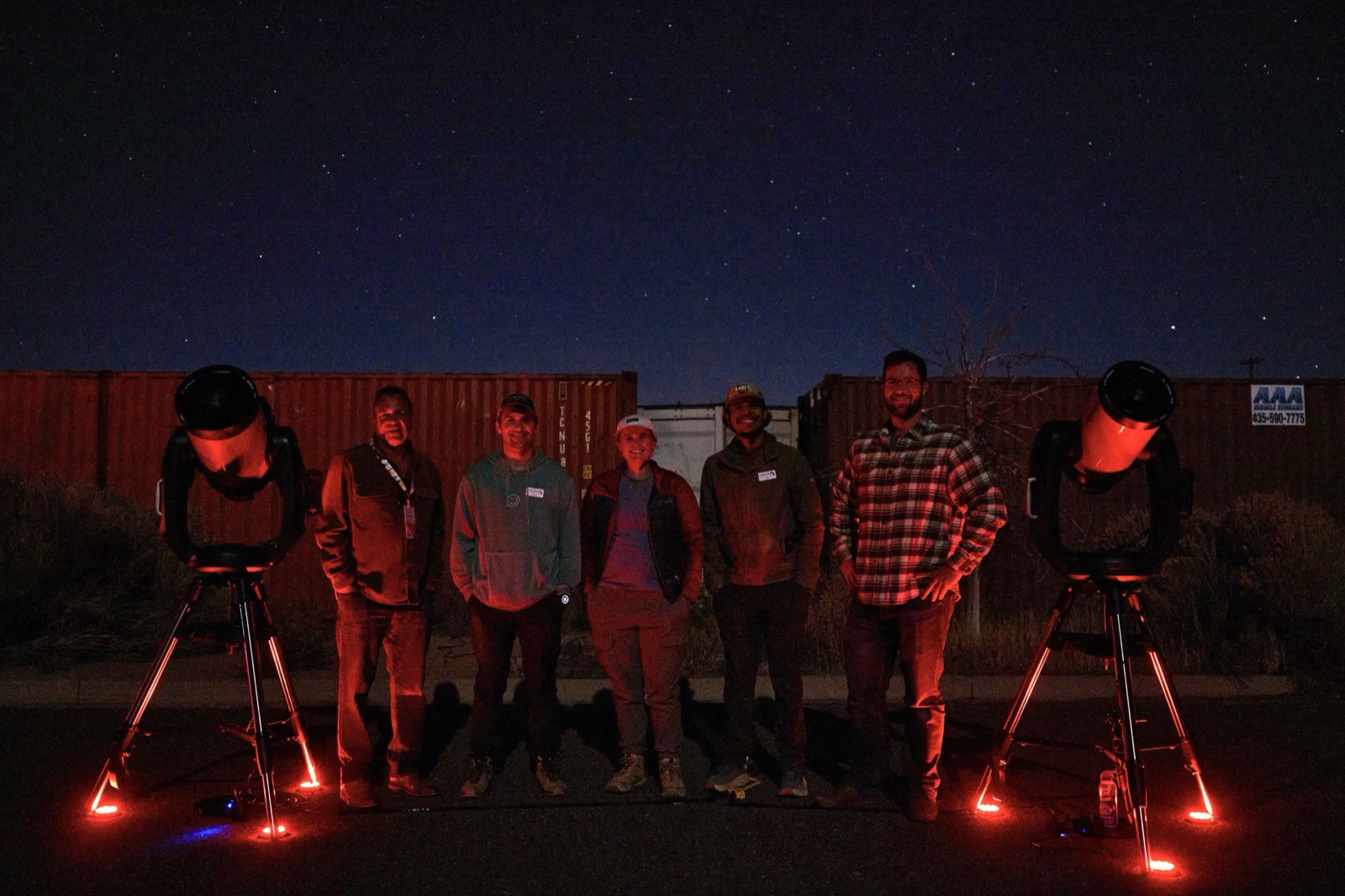A family group gathered around telescopes at a night sky event